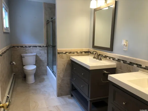 a spacious bathroom with a double vanity sink a mirror and a toilet