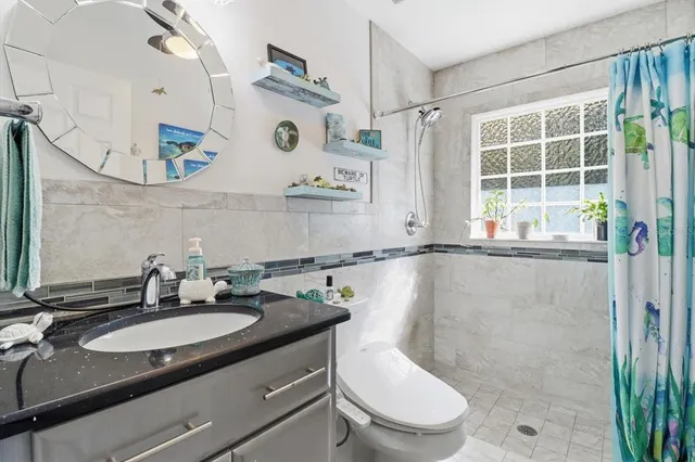 a bathroom with a granite countertop sink toilet a mirror and shower