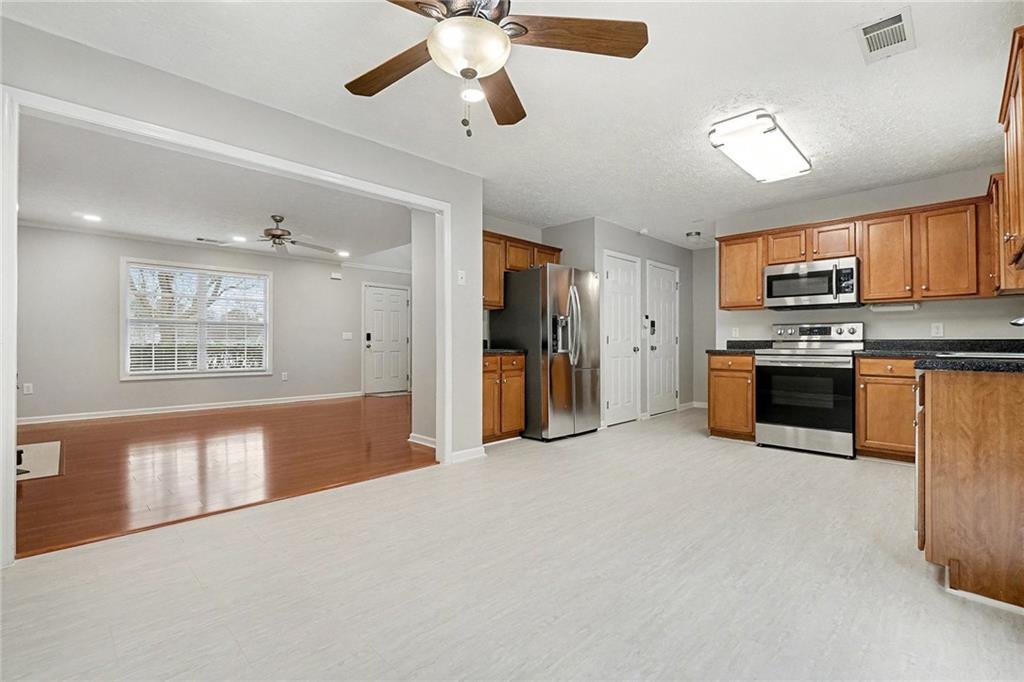 307 Remington Pl Boulevard Dallas, GA 30157 - Photo 8 of 27 a view of a kitchen with a stove cabinets a ceiling fan and wooden floor