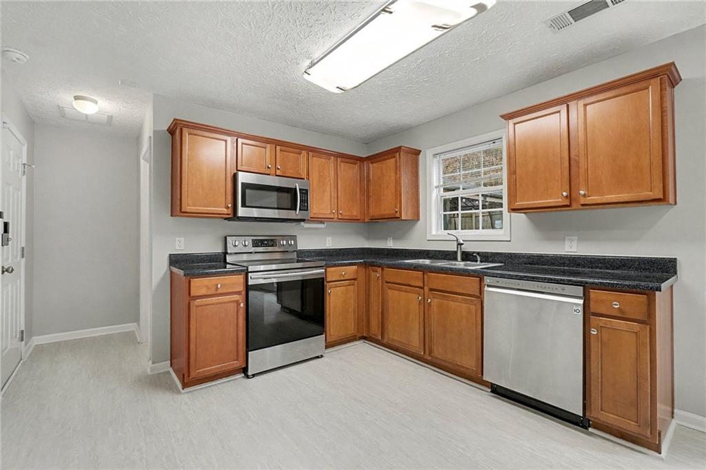 307 Remington Pl Boulevard Dallas, GA 30157 - Photo 9 of 27 a kitchen with stainless steel appliances granite countertop a stove sink microwave and cabinets