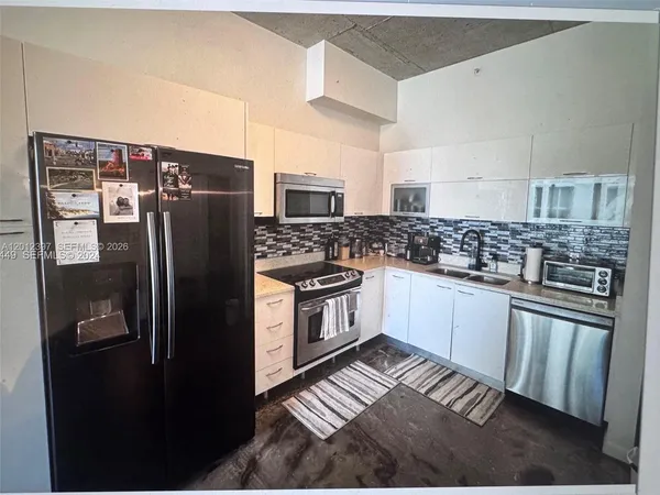 a kitchen with stainless steel appliances granite countertop a refrigerator a stove and a sink