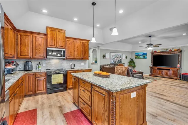 a kitchen with stainless steel appliances granite countertop a sink dishwasher and a stove with wooden floor