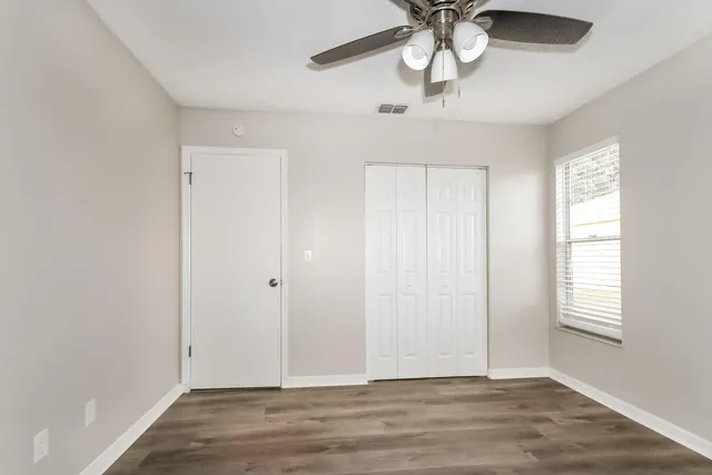 a view of an empty room with window and chandelier fan