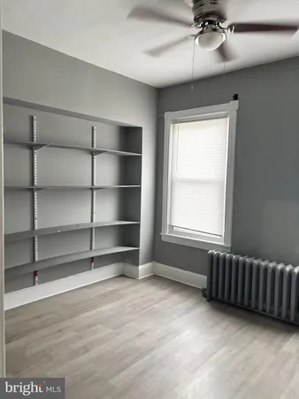 an empty room with wooden floor fan and windows