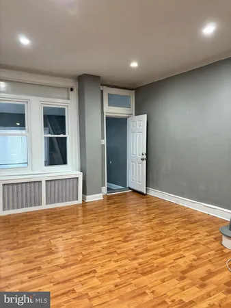 a view of an empty room with window and wooden floor