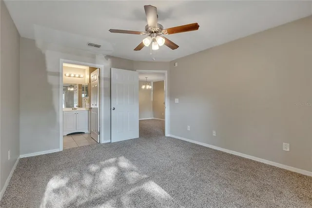 a view of a livingroom with a chandelier fan and windows