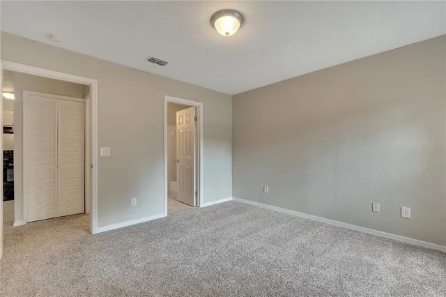 an empty room with closet and windows