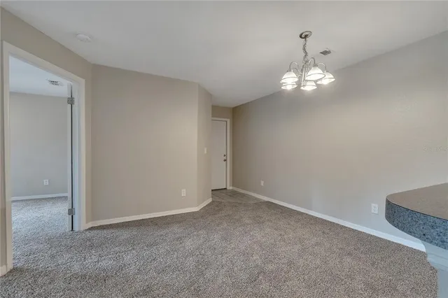 an empty room with a chandelier fan and wooden floor