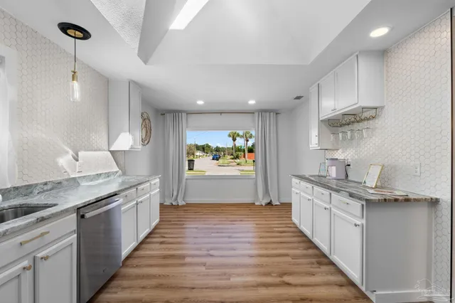 a large kitchen with stainless steel appliances granite countertop a lot of counter space and wooden floors