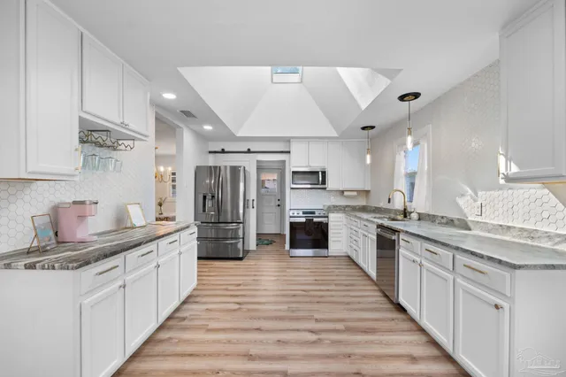 a large white kitchen with stainless steel appliances