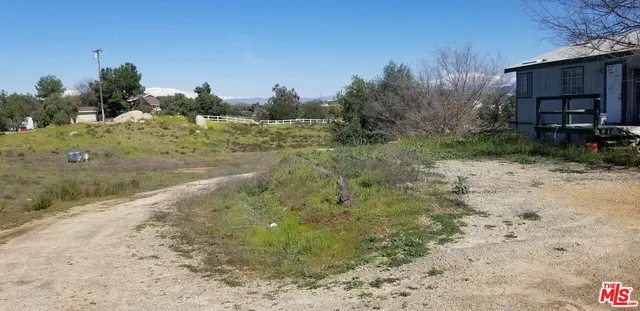 a view of a dry yard with wooden fence