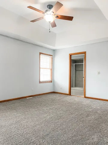 an empty room with chandelier fan and windows