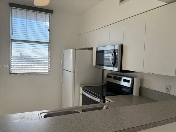 a room with a wooden floor and stainless steel appliances