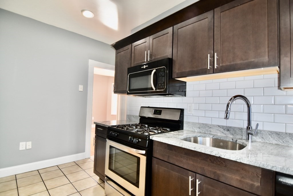 21 Treadway Road, Unit 2 Boston, MA 02125 - Photo 17 of 21 a kitchen with stainless steel appliances a sink a stove a microwave and cabinets