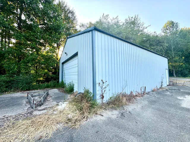 a backyard of a house with plants and trees with wooden fence