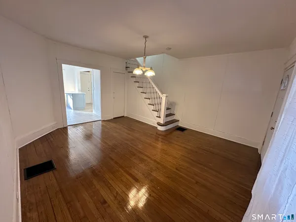 a view of a room with wooden floor staircase and a kitchen