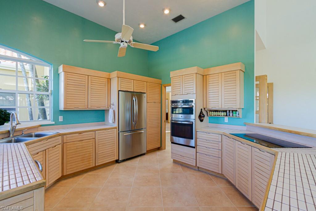 4401 Pond Apple Drive South Naples, FL 34119 - Photo 14 of 35 a kitchen with stainless steel appliances kitchen island granite countertop a refrigerator and a sink