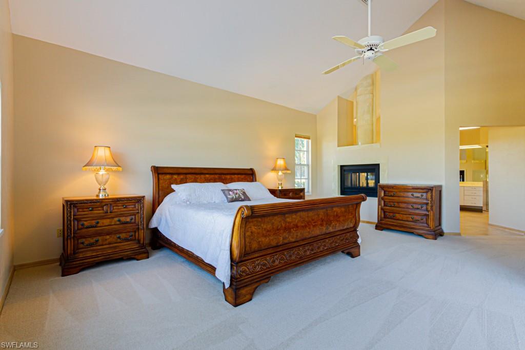 4401 Pond Apple Drive South Naples, FL 34119 - Photo 18 of 35 a spacious bedroom with a bed and a chandelier
