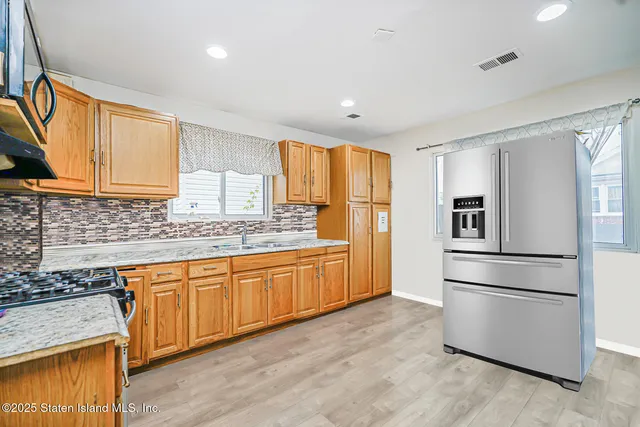 a kitchen with granite countertop stainless steel appliances a refrigerator cabinets and wooden floor