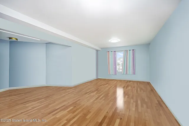 a view of an empty room with window and wooden floor