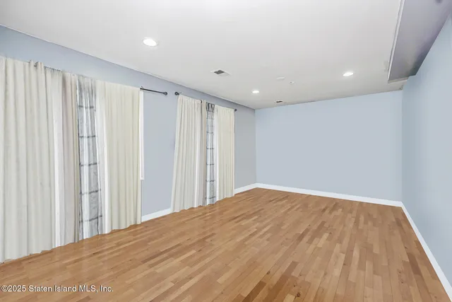 a view of a big room with wooden floor and entryway