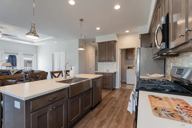 a kitchen with a stove a sink a refrigerator and chairs