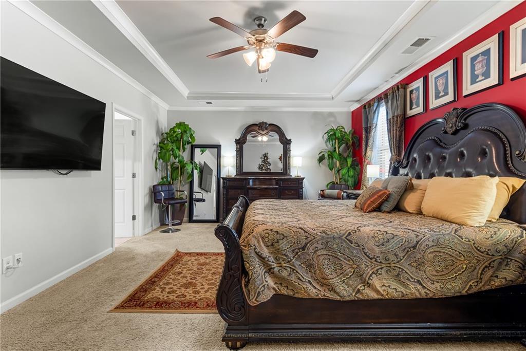 1476 Harlequin Way Stockbridge, GA 30281 - Photo 23 of 57 a bedroom with a bed a mirror on dresser and a flat screen tv