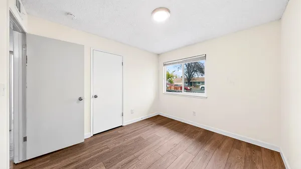 an empty room with wooden floor and window