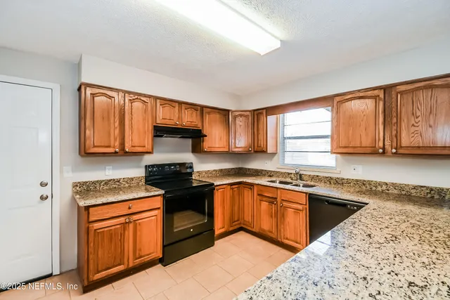 a kitchen with stainless steel appliances granite countertop wooden cabinets granite counter tops and a window