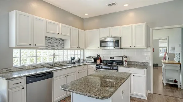 a kitchen with granite countertop a refrigerator stove and microwave