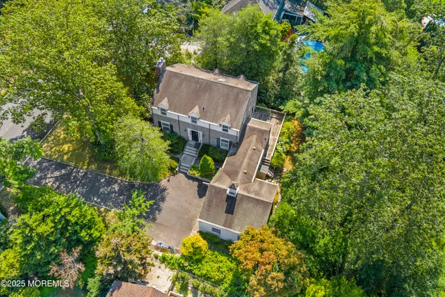 an aerial view of a house with a yard and trees all around