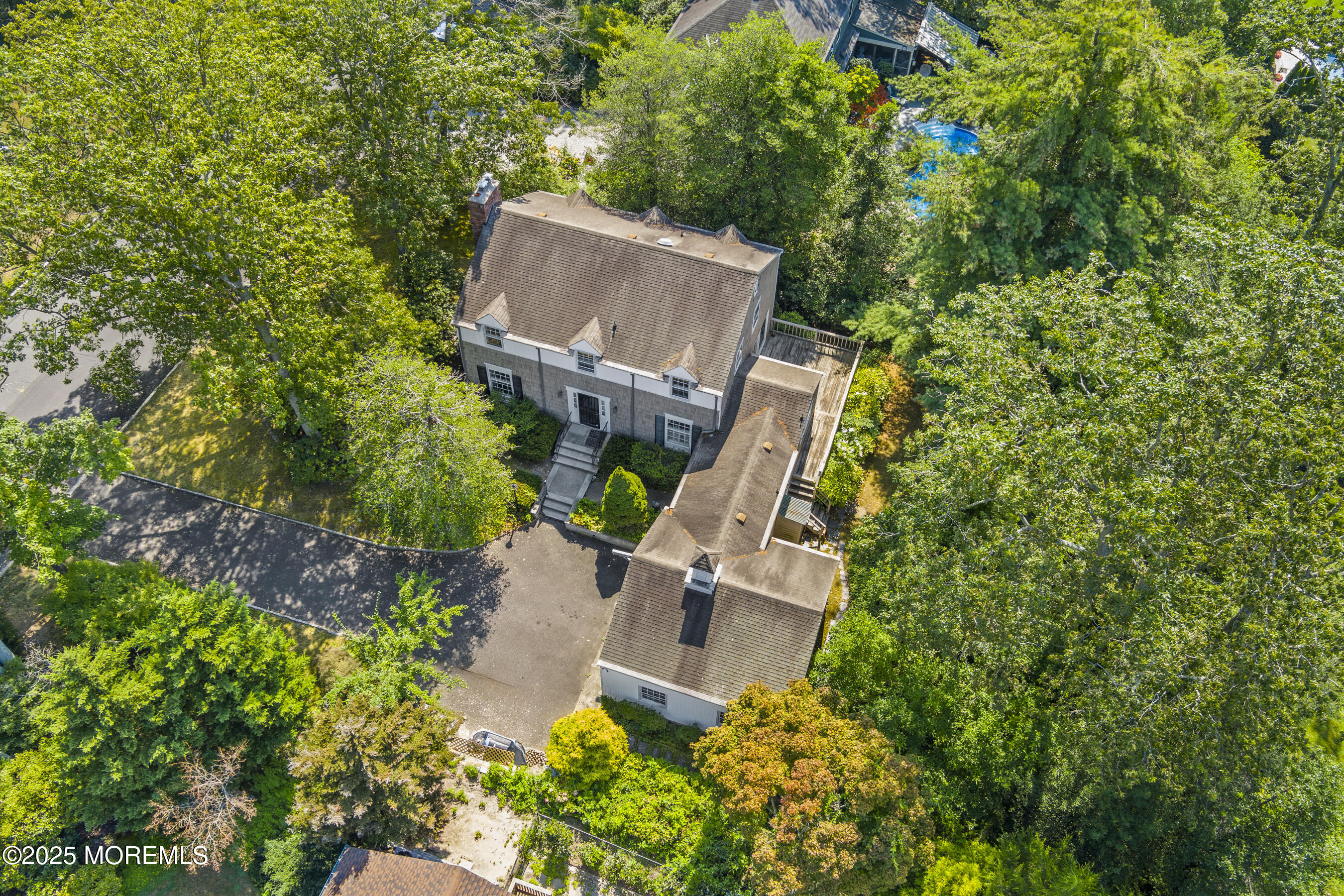 an aerial view of a house with a yard and trees all around
