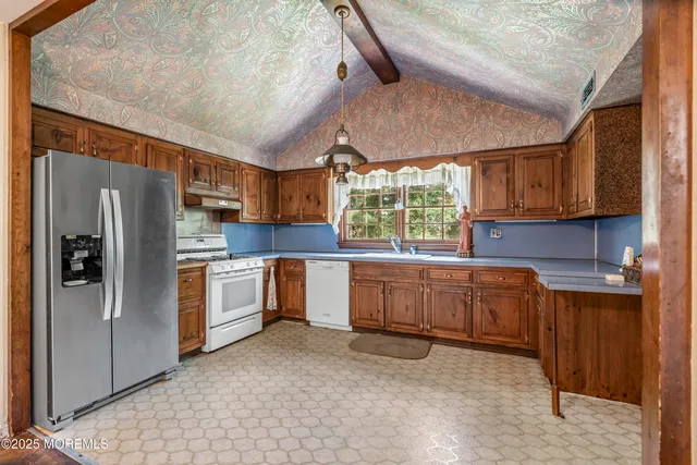 a kitchen with granite countertop a refrigerator and wooden cabinets