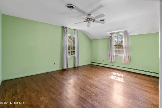 an empty room with wooden floor chandelier fan and windows
