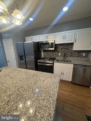 a kitchen with stainless steel appliances kitchen island granite countertop a refrigerator a stove and a sink with granite countertops