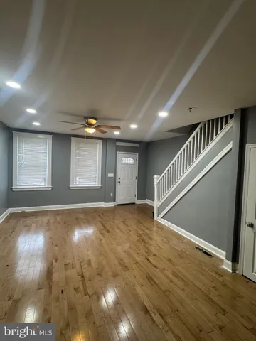 a view of an empty room with wooden floor and stairs