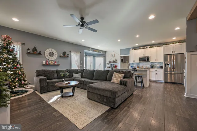a living room with furniture and kitchen view with wooden floor