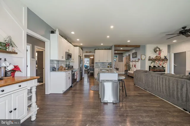 a living room with furniture and kitchen view with wooden floor