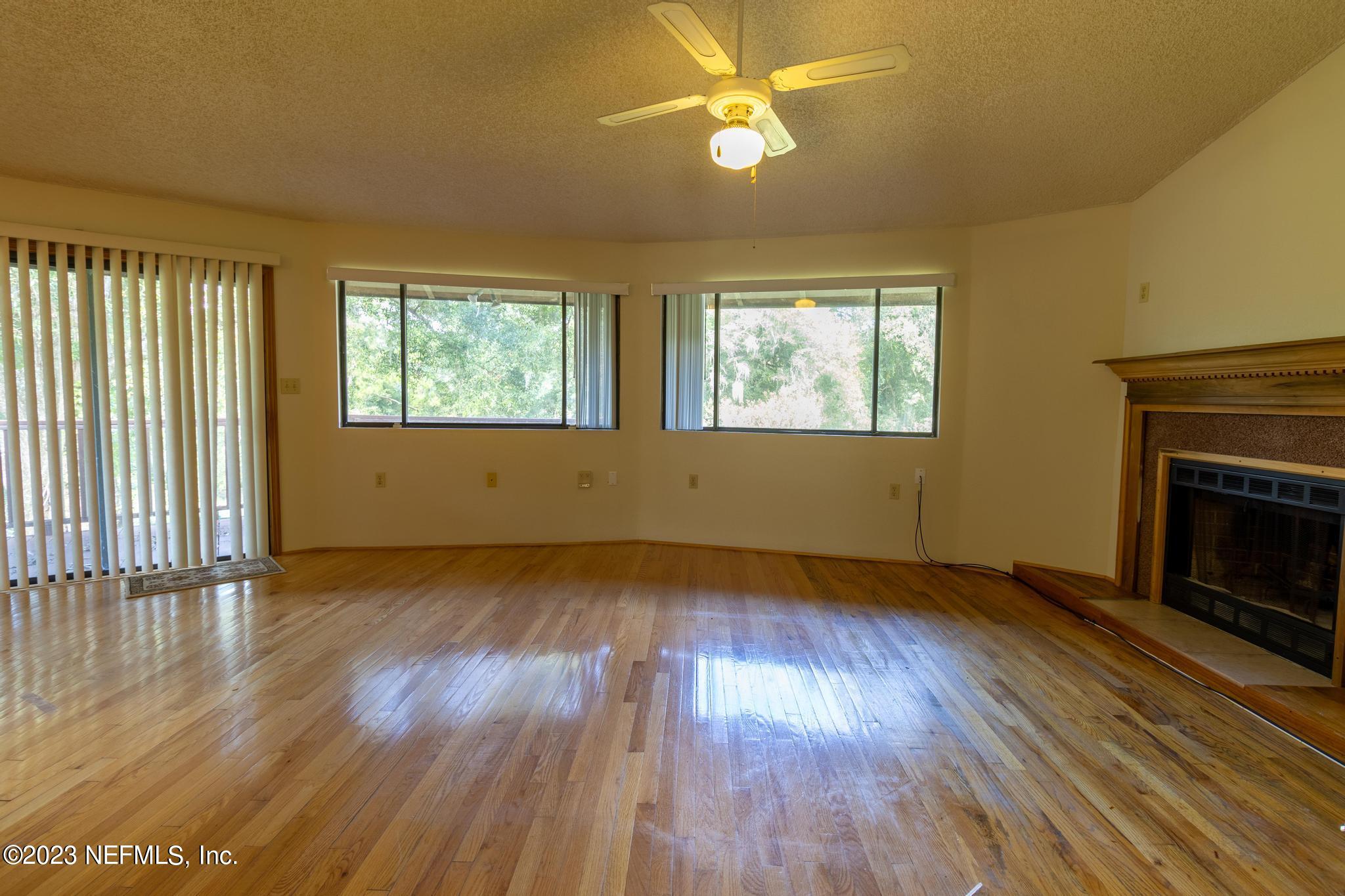 1151 Southeast 46th Loop Keystone Heights, FL 32656 - Photo 9 of 39 an empty room with wooden floor fireplace and windows