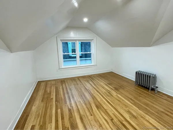a view of an empty room with wooden floor and bench