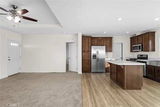 a kitchen with stainless steel appliances granite countertop a refrigerator a sink dishwasher a stove with wooden cabinets and floor