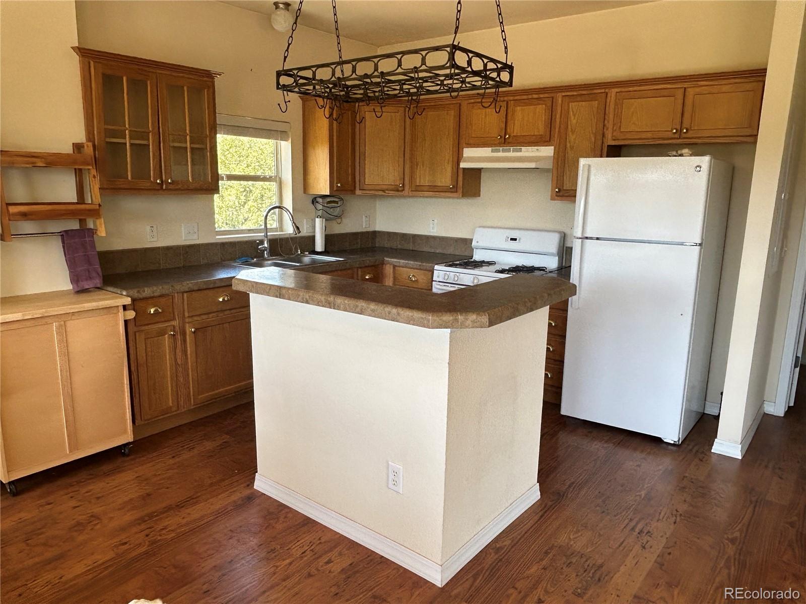 52601 County Rd LL56 Villa Grove, CO 81155 - Photo 6 of 33 a kitchen with a sink a refrigerator a stove and wooden floor