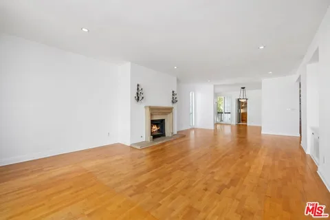 a view of empty room with wooden floor and fireplace