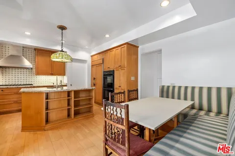 a kitchen with stainless steel appliances kitchen island granite countertop a table chairs in it and wooden floors