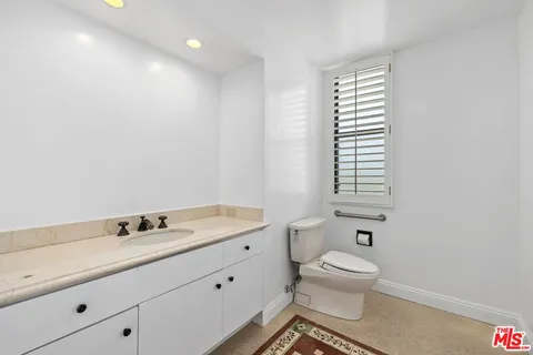 a bathroom with a toilet a sink a mirror and a window