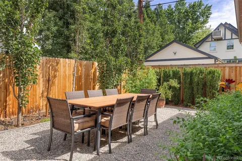 a patio with table and chairs and potted plants