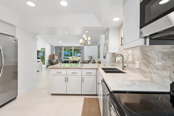 a kitchen with granite countertop a sink stainless steel appliances and white cabinets