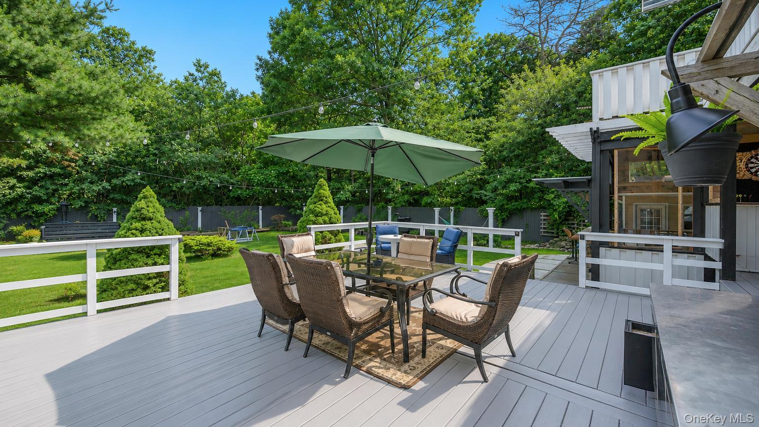 19 Joan Road Bay Shore, NY 11706 - Photo 48 of 50 Expansive light-gray decking with white railings, featuring a glass-top dining table with wicker chairs