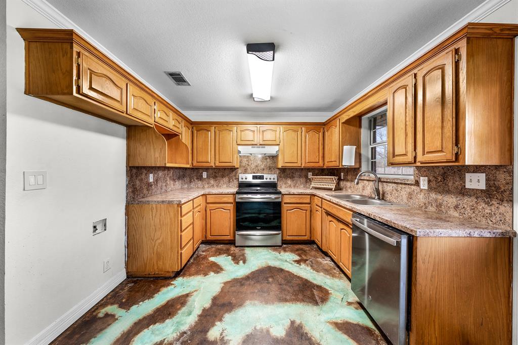 903 Amy Way Bonham, TX 75418 - Photo 10 of 27 Kitchen featuring stainless steel appliances, wood finish cabinets, crown molding, light countertops, and a textured ceiling