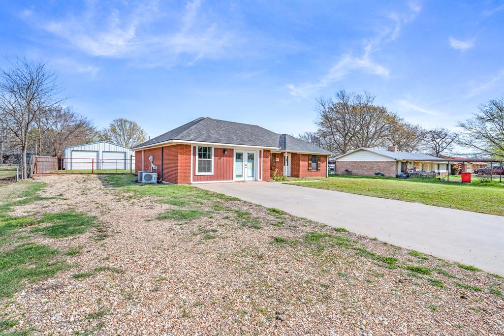 903 Amy Way Bonham, TX 75418 - Photo 3 of 27 Ranch-style home with an outdoor structure, driveway, a garage, brick siding, and a shingled roof